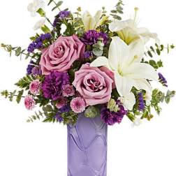 Pink roses and white lilies in a purple glass vase