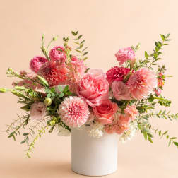 Pink floral arrangement in a white vase with roses and dahlias