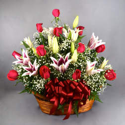 Basket arrangement of red roses and white lilies with a red ribbon