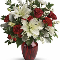 Red roses and white lilies in a red glass vase