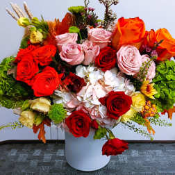 Mixed roses and hydrangeas arranged in a white vase