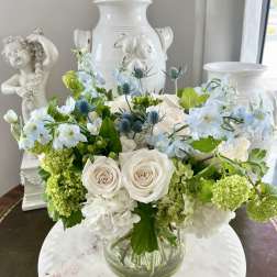 White and blue floral arrangement in a clear glass vase