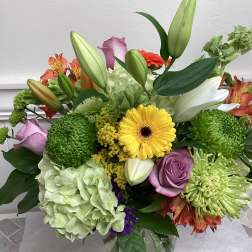 Mixed bouquet in a glass vase with lilies, roses, hydrangea, and chrysanthemums