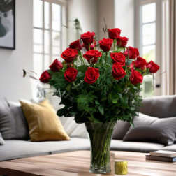 Red roses arranged in a clear glass vase on a table