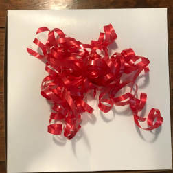 Red curly ribbon bow on a white gift box