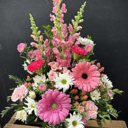 Pink and white mixed flower arrangement in a white basket vase