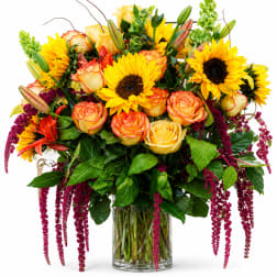Bouquet of yellow sunflowers and peach roses in a glass vase