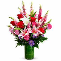 Bouquet of red and pink roses with white lilies in a green glass vase