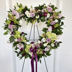 Heart-shaped floral wreath on an easel with a purple ribbon