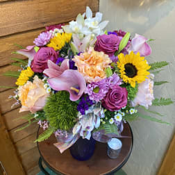 Mixed bouquet with sunflowers, roses, lilies, and calla lilies in a vase