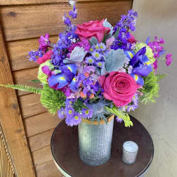 Bright mixed bouquet in a ribbed metal vase with pink roses and purple flowers