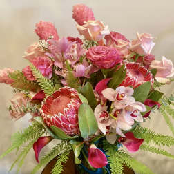 Pink and red tropical bouquet with roses, orchids, and protea in a vase