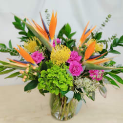 Tropical bouquet with orange bird-of-paradise and pink flowers in a glass vase