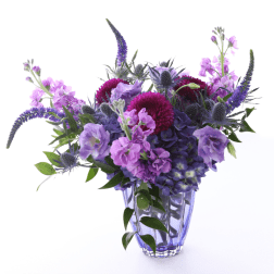 Purple and pink flowers arranged in a clear glass vase