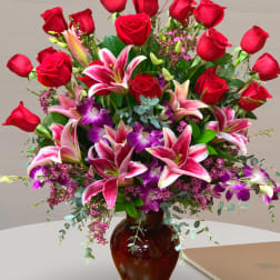 Large bouquet of red roses and pink lilies in a brown glass vase