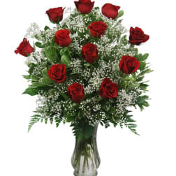 Red roses arranged in a clear glass vase with white filler flowers