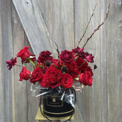 Red roses arranged in a black hat box with clear wrap
