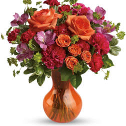 Orange roses and purple flowers in an amber glass vase
