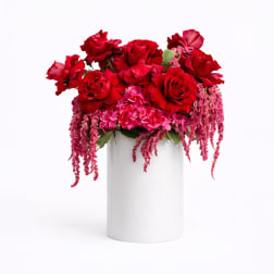 Red rose arrangement in a white cylindrical vase