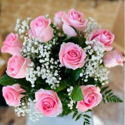 Pink roses arranged with white baby's breath in a vase