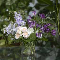 Purple and blush flowers arranged in a clear glass vase