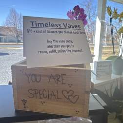 Store display sign for reusable vases with orchids in the background