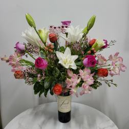 Bouquet of lilies, roses, and pink alstroemeria in a wine bottle vase