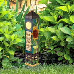 Decorative garden stake with painted flowers among green plants