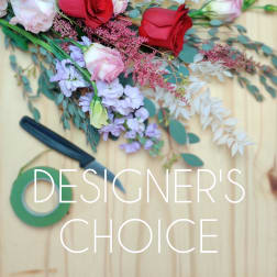 Assorted roses and pastel flowers with greenery on a wooden surface