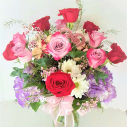 Bouquet of red and pink roses with purple flowers in a glass vase