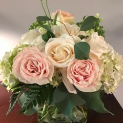 Pink and cream roses arranged in a glass vase