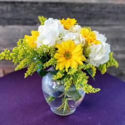 Yellow and white flowers arranged in a clear glass vase