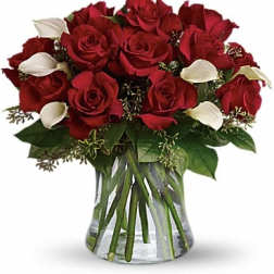 Bouquet of red roses and white calla lilies in a clear glass vase