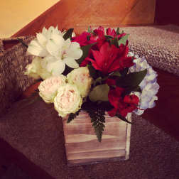 Mixed bouquet of white, red, and pale pink flowers in a wooden box