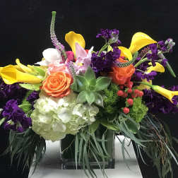 Colorful floral arrangement with calla lilies, roses, hydrangea, and succulents in a glass vase