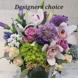 Mixed bouquet with orchids, roses, and purple allium in a dark vase