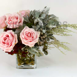 Pink roses arranged in a clear glass vase with silvery foliage