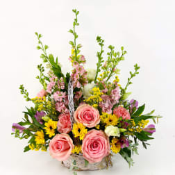Basket arrangement with pink roses, yellow flowers, and tall pink blooms
