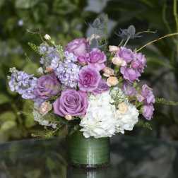 Lavender roses and white hydrangeas in a green glass vase