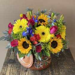 Bright mixed bouquet with sunflowers, gerbera daisies, roses, and irises in a decorative pot