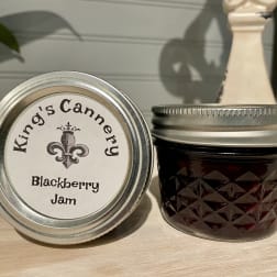 Two jars of blackberry jam on a wooden surface