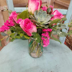 Pink roses and a succulent arranged in a glass jar vase