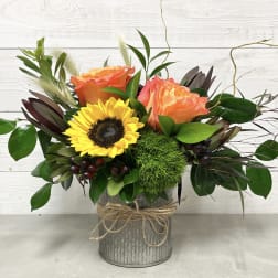Bouquet of orange roses and a yellow sunflower in a metal vase