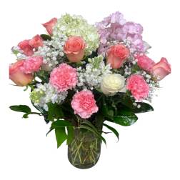 Pink roses and carnations in a glass vase with white and lavender blooms