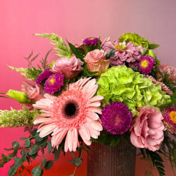 Pink and purple mixed flower arrangement in a vase with a bright green hydrangea