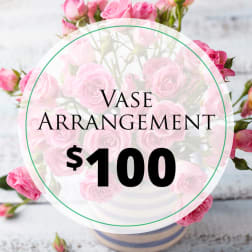 Pink rose arrangement in a vase with a $100 label