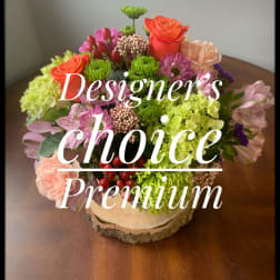 Mixed bouquet in a wood slice base with pink, orange, and green blooms