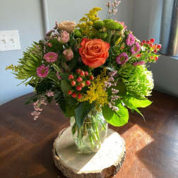 Mixed bouquet in a glass vase with an orange rose and pink flowers