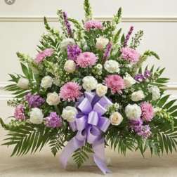 Large pink and white floral arrangement with a purple ribbon bow