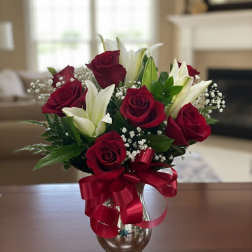 Bouquet of red roses and white lilies in a glass vase with a red ribbon
